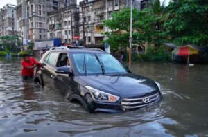 SUV crossing a waterlogged city road during heavy monsoon rain